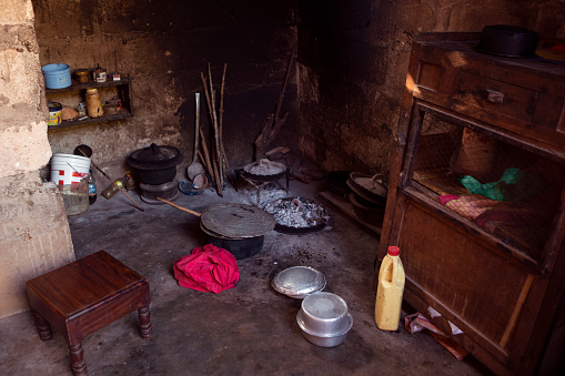 Modest kitchen in african village. Old-fashoned poor kitchen with open bonfire place and stove, wall covered with soot, visible pots and other kitchen utensils. Real life kitchen in developing countries.