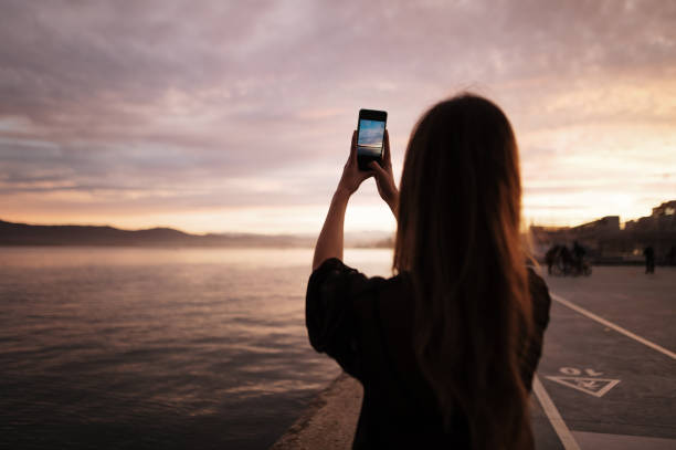 istock Young woman taking a picture of a sunset 1299457121