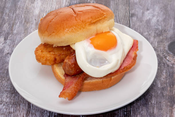 istock Breakfast brioche roll with a fried egg, hash brown, sausage, and bacon 1299457283