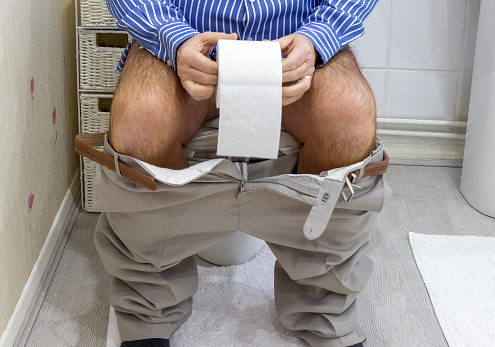 Low section of man defecating in the toilet