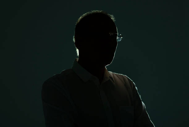 istock Male silhouette with backlit and shadow in glasses 1299460879