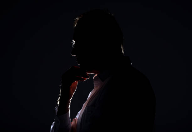 istock Male silhouette with backlit and shadow in glasses 1299460888