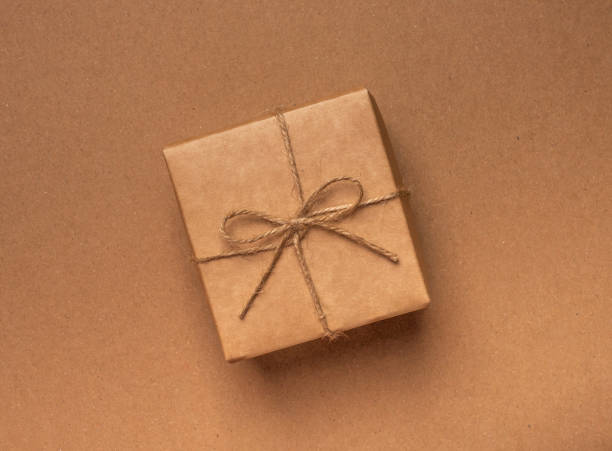 istock Gift box wrapped in craft paper with jute bow on kraft eco background 1299460916