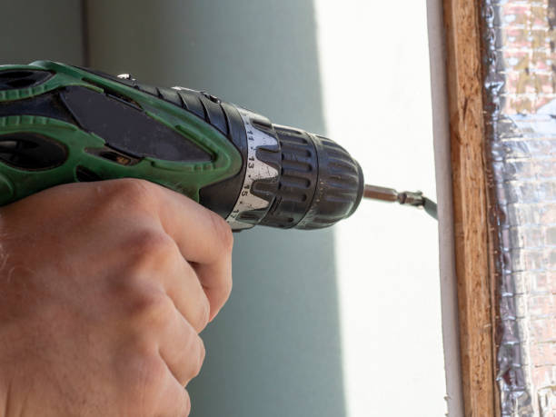 istock a man is holding a screwdriver and twisting the screw into the drywall. selective focus 1299462173