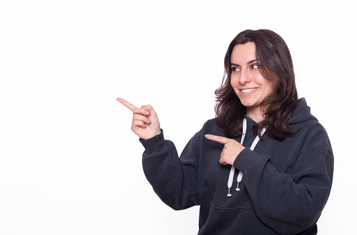 Beautiful woman is pointing at copy space with her fingers in front of white background.