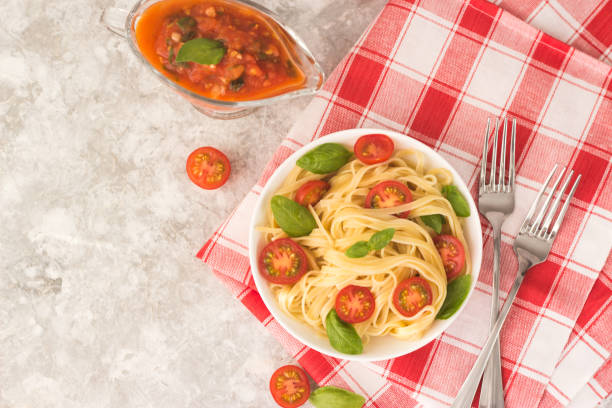 istock pasta marinara in a white plate on a white table with tomato wedges and basil leaves 1299465482