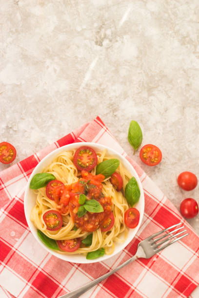 istock pasta marinara in a white plate on a white table with tomato wedges and basil leaves 1299465674