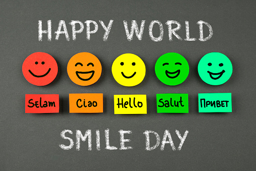 Colorful smileys ,the word hello in several languages and text: Happy world smile day, on chalkboard background