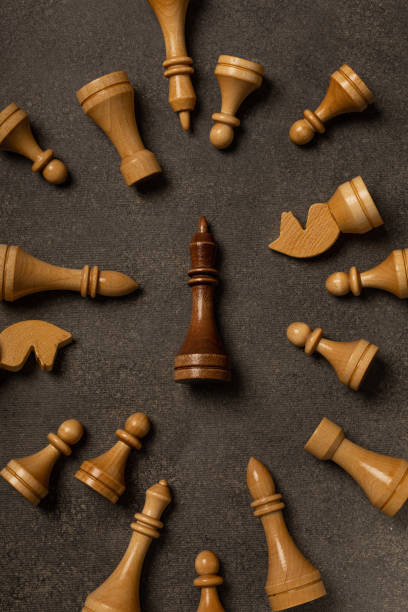 istock Black king among white chess pieces on dark background 1299466649