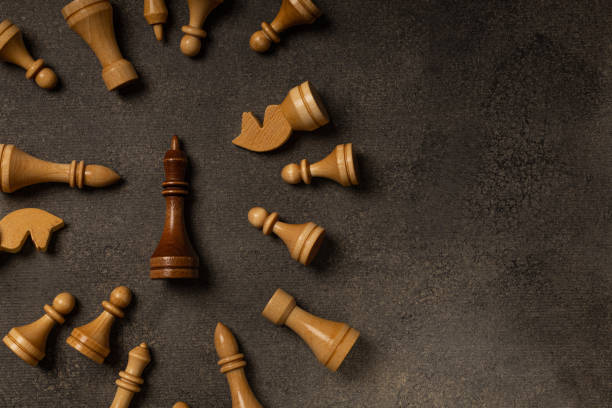 istock Black king among white chess pieces on dark background 1299466704