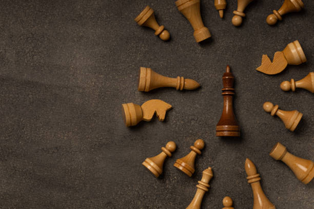 istock Black king among white chess pieces on dark background 1299466710