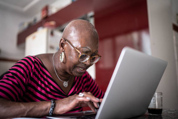 istock Senior woman using laptop at home 1299469360