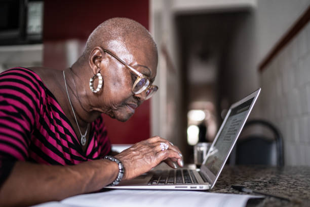 istock Senior woman using laptop at home 1299469400