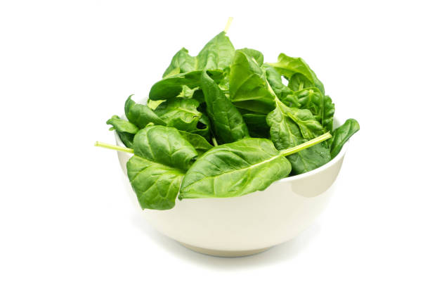 istock Young spinach in bowl solated on white background 1299471350
