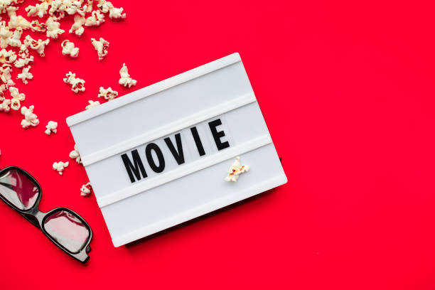 istock Popcorn, 3D glasses and lightbox text Movie time on red paper background. Top view Template 1299471352
