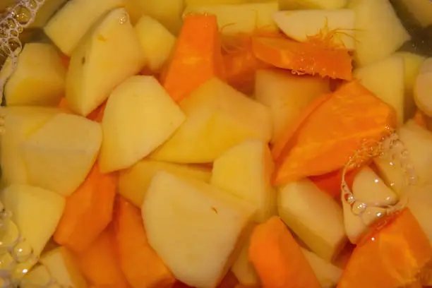 cut potatoes with pumpkin in a water pot with view from above