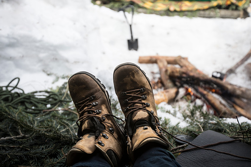 Personal Perspective of a Man Sitting Down By a Log Fire in Wet Hiking Boots.