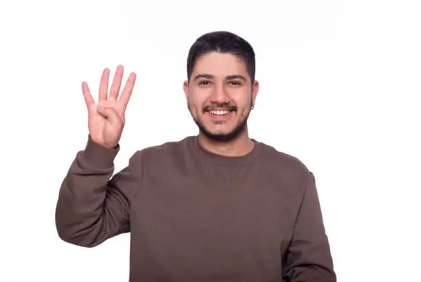 Handsome young man standing in front of white background counting one to five with his fingers.