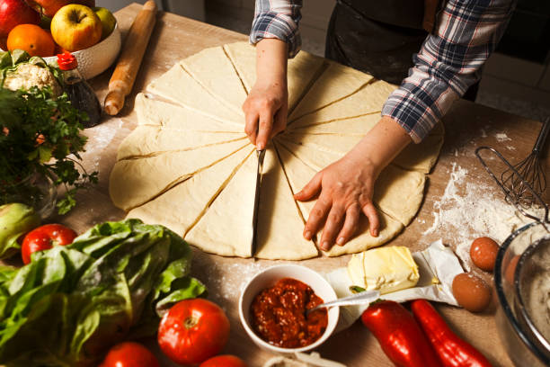 istock Young woman making dough for pizza rolls cutting shape 1299486680