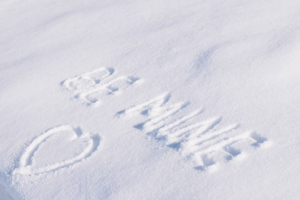 istock Phrase Be mine and drawing in the shape of a heart on white snow 1299486805