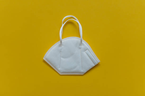istock FFP3 mask lie on the table, top view, on a yellow background 1299487474
