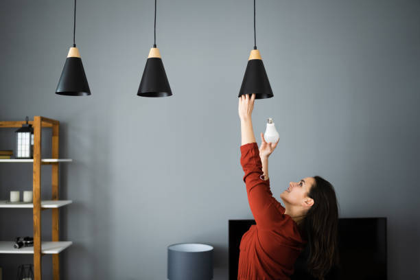 femme changeant l’ampoule cassée - led bulb photos et images de collection