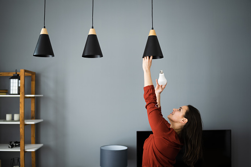 Woman Changing Broken Light Bulb To LED