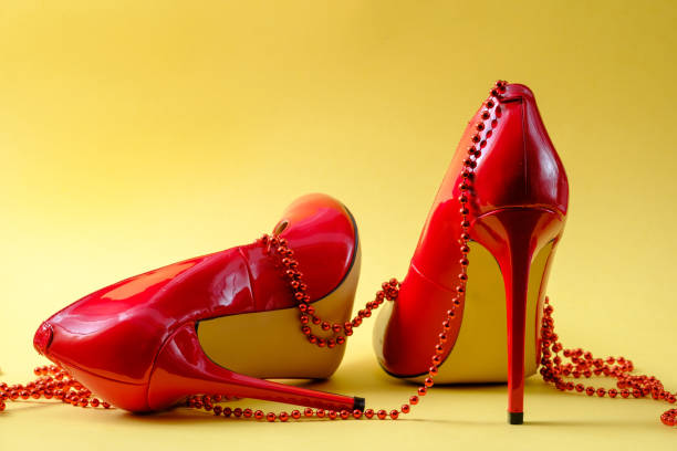 istock female shiny red stilettos on a yellow background 1299487705