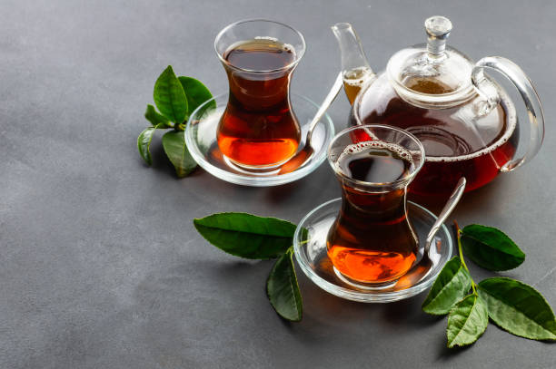 taza de cristal de té negro con hojas de té fresco, bebida caliente tradicional de elaboración turca - tea cup cup china saucer fotografías e imágenes de stock