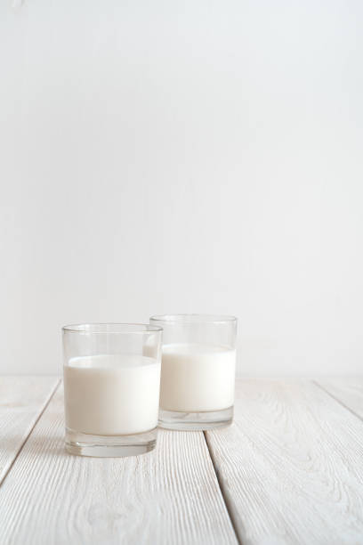 istock Two glasses of milk on a white background. Side view with copy space, vertical orientation 1299487980