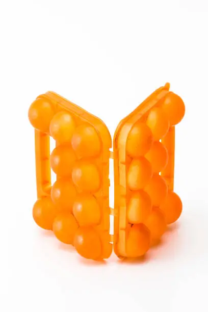 Picture of Open Empty Obsolete Orange Egg Hiolder. Placed Against White Background. Vertical