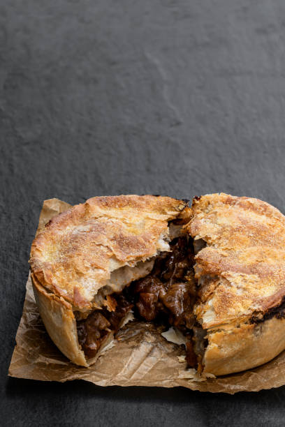 istock Puff pastry steak pie on baking paper on stone background 1299489259