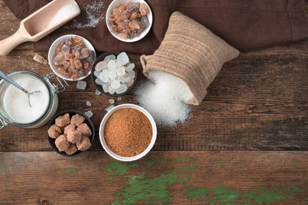 White and cane sugar in different forms on a wooden background