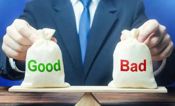 Photo of Businessman holds good and bad bags on scales. Evaluating the actions of other people, weighing the positive and negative qualities. Good and evil, karma. Introspection. Ethics and acceptability.