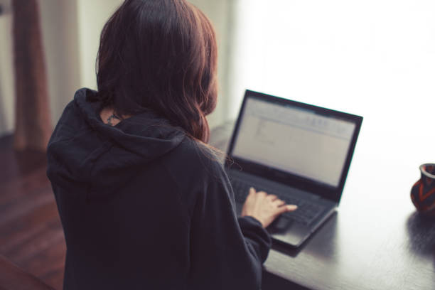 istock Woman working on laptop at home from back view 1299491050