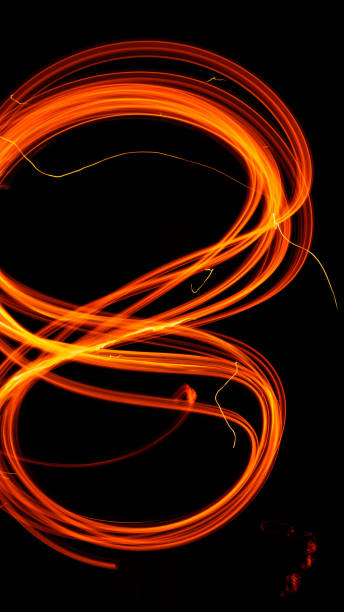 istock Drawing shapes with fire at night, infinity sign, bright colors on night background, fun with fire. 1299491475