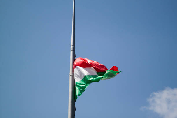 istock Hungarian flag on a blue sky with clouds background 1299493490