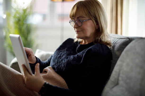istock Smiling senior woman using digital tablet at home 1299493617