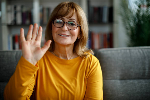 istock Portrait of smiling senior woman making hello gesture 1299493692