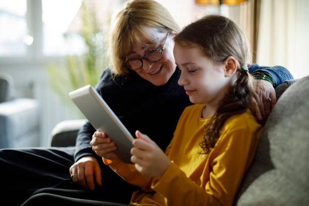 istock Smiling granddaughter and grandmother using digital tablet on sofa 1299494482