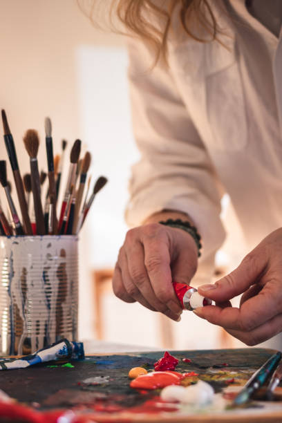 Artist mixing acrylic colors on palette for painting Female artist mixing acrylic colors on palette for painting. Woman working in art studio. Palette and paintbrush on table abstract oil painting for beginners stock pictures, royalty-free photos & images