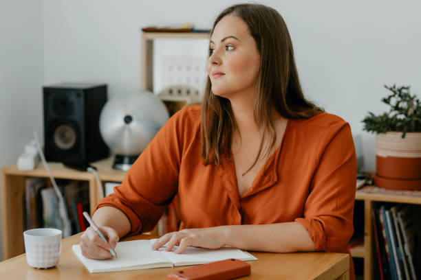 istock Beautiful  plus size Woman Sitting in her Living Room and Writing a Diary 1299496003