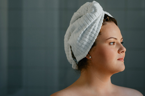 A portrait of a pretty plus size woman in the bathroom after a morning shower.