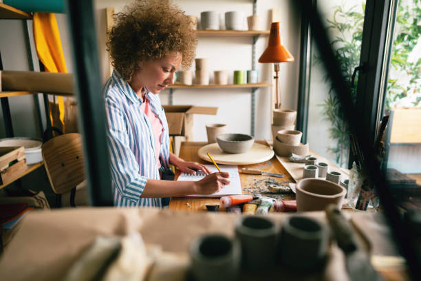 istock Craftswoman at her work taking notes in her small business pottery studio 1299496143