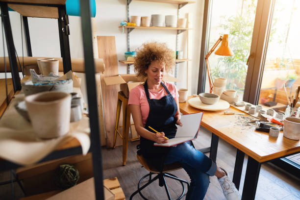 istock Caucasian ethnicity woman with a planner book in her creative pottery studio 1299496146