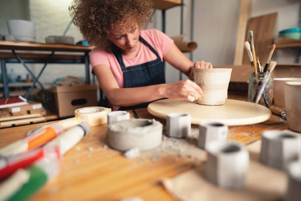 istock Craftswoman preparing flowerpot for coloring in her small creative studio 1299496164