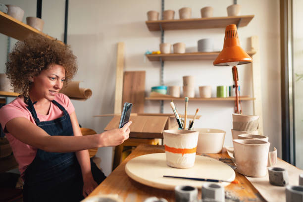istock Women artisan taking a photo in her pottery studio 1299496170