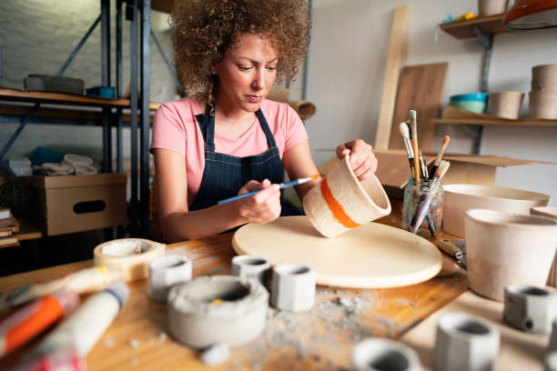 istock Craftswoman painting concrete flowerpot in a creative pottery studio 1299496184