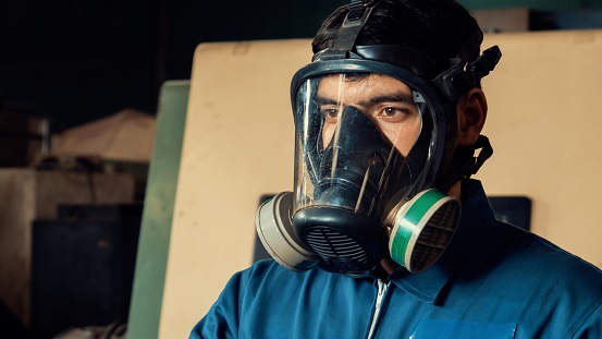 Skillful worker wears gas mask in the factory . Industrial people and manufacturing labor concept .