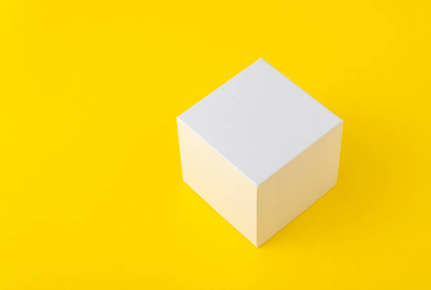 istock White cardboard box of square shape on yellow background. Copy space. Mock up. 1299496590